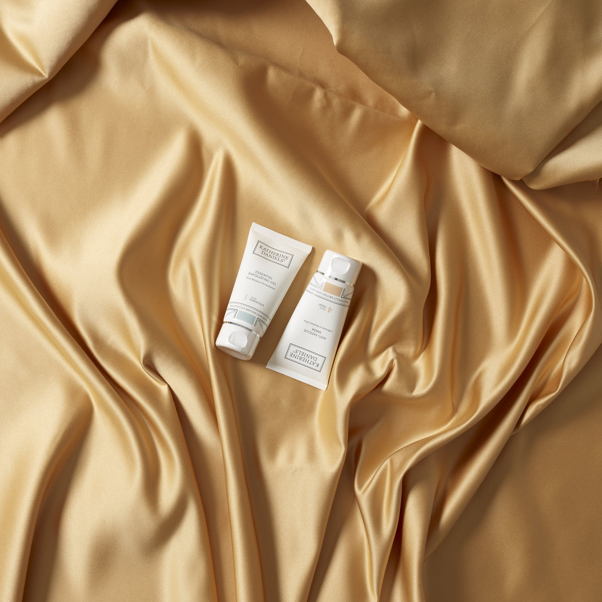 Anti-Fatigue Mask and Essential Exfoliating Gel on gold fabric